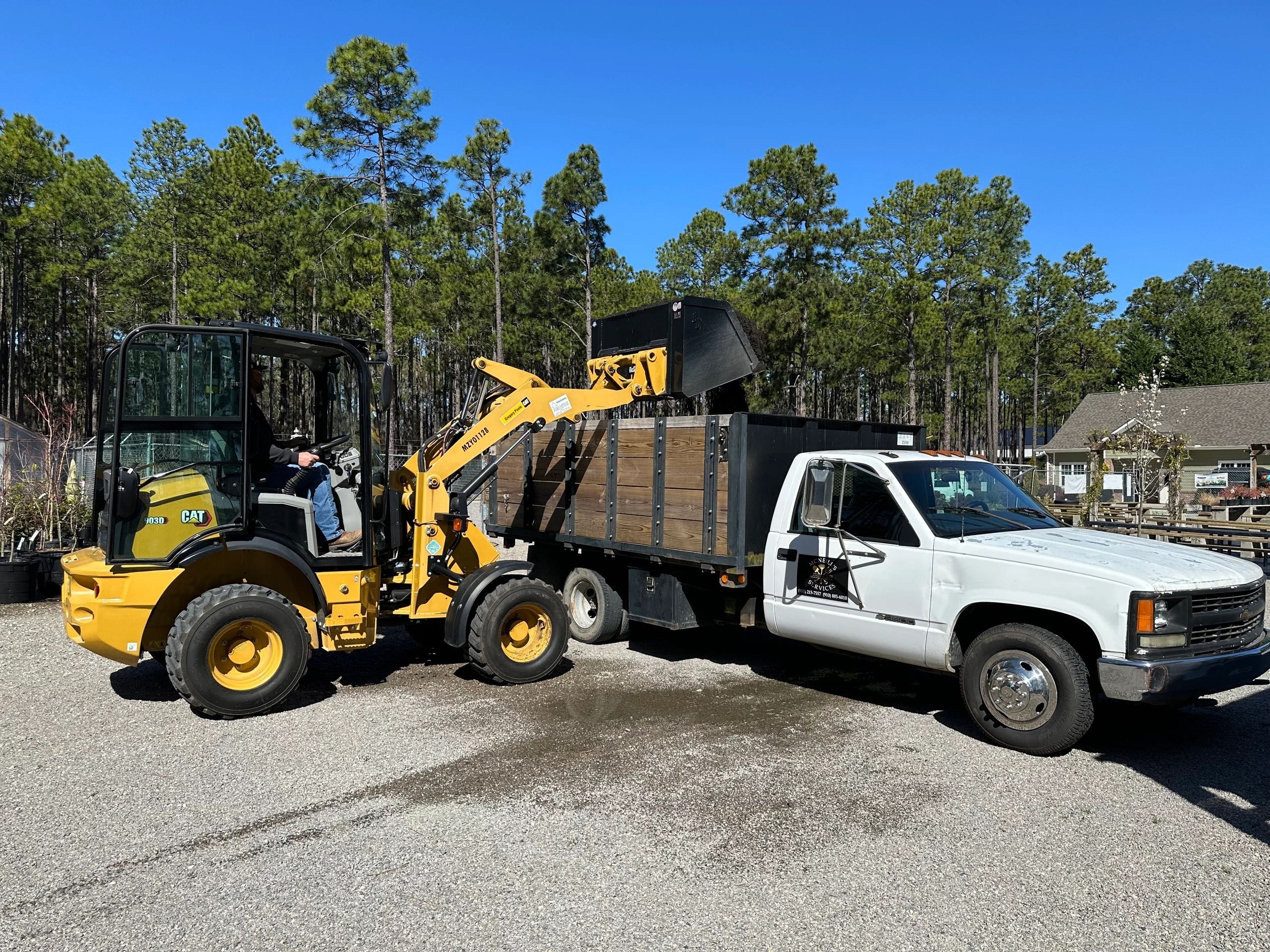 CAT loader dumping bulk topsoil into a dump truck